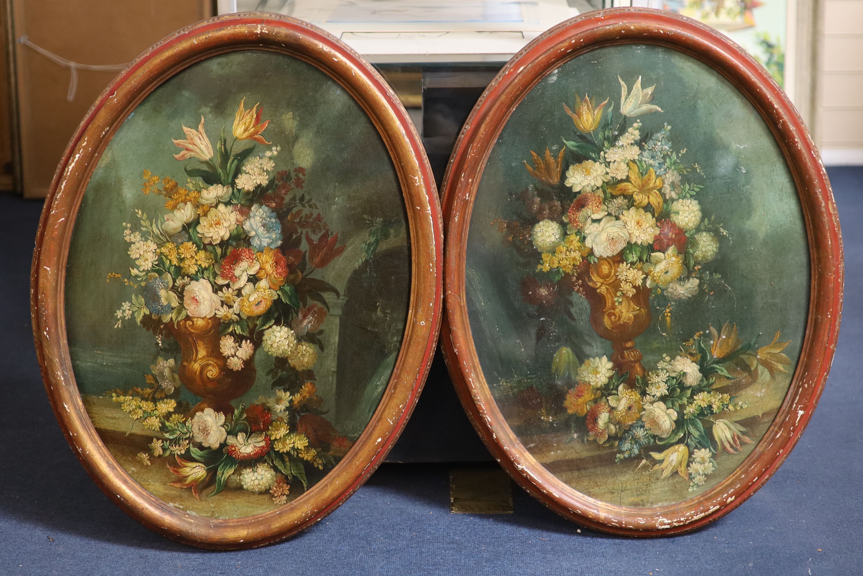19th century Italian School , Still lifes of flowers in vases, an arch and water beyond, pair of oils on wooden panels, ovals, 65 x 47cm